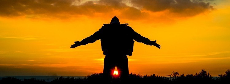 Silhouette of man on hill yelling to the world